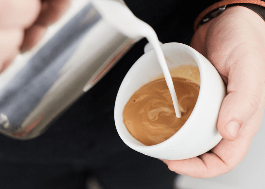 Pouring Milk into Coffee Cup